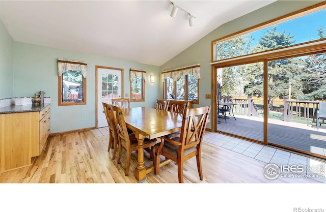 dining space featuring lofted ceiling, track lighting, healthy amount of natural light, and light wood finished floors