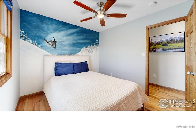 bedroom featuring wood finished floors, baseboards, and a ceiling fan