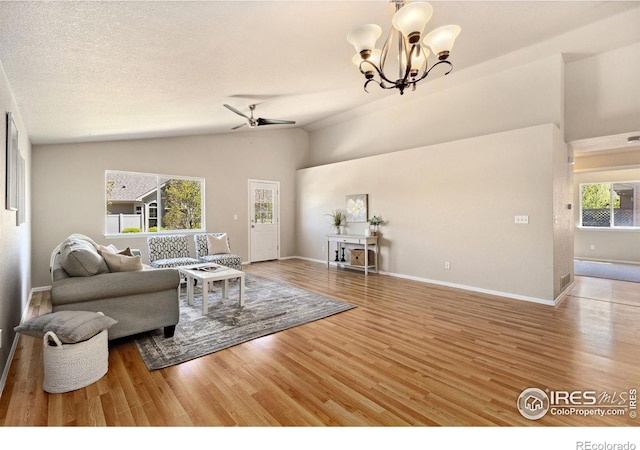 living room with wood finished floors, a ceiling fan, baseboards, a chandelier, and high vaulted ceiling