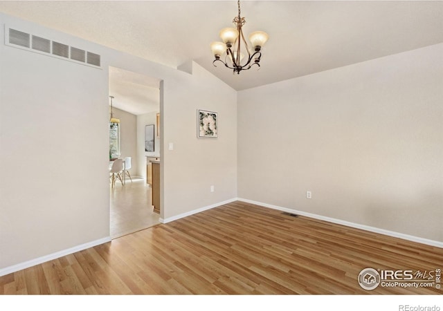 spare room with a chandelier, lofted ceiling, light wood-style flooring, and baseboards