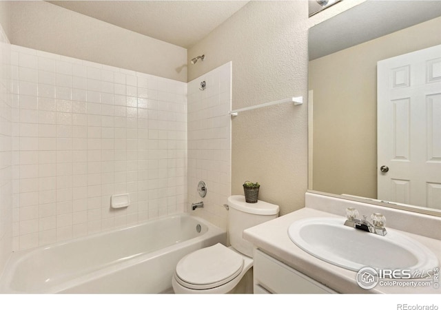 bathroom with a textured wall, toilet, bathtub / shower combination, and vanity