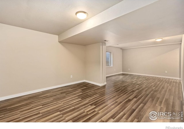 basement with baseboards and dark wood-style flooring