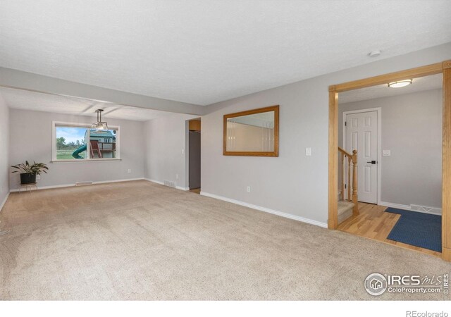 carpeted empty room with stairway, baseboards, and a smoke detector