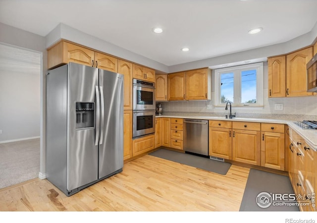 kitchen with stainless steel appliances, light countertops, light wood finished floors, decorative backsplash, and baseboards