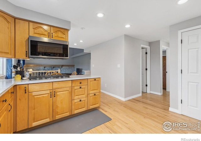 kitchen with appliances with stainless steel finishes, light wood-style floors, baseboards, decorative backsplash, and recessed lighting