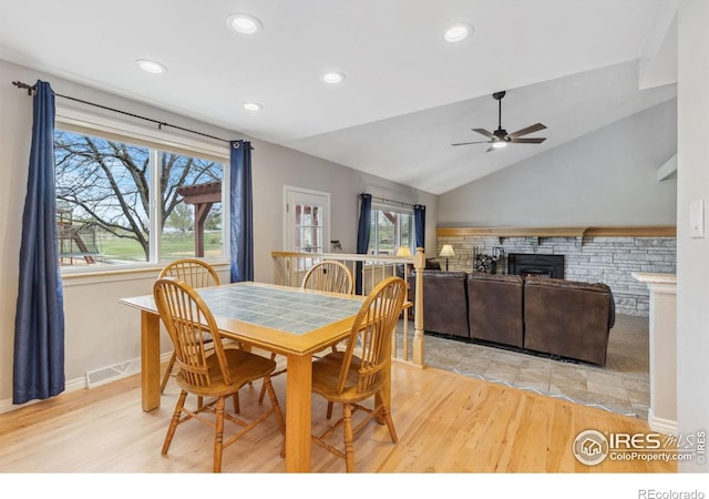 dining area featuring ceiling fan, light wood-type flooring, plenty of natural light, recessed lighting, and a stone fireplace