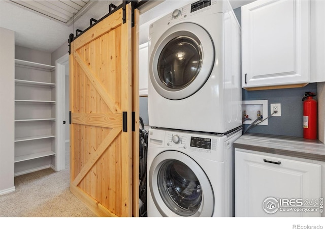 laundry room featuring stacked washing machine and dryer, cabinet space, a barn door, and carpet floors