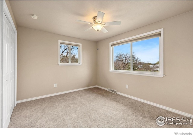 unfurnished bedroom featuring carpet, baseboards, a closet, and ceiling fan