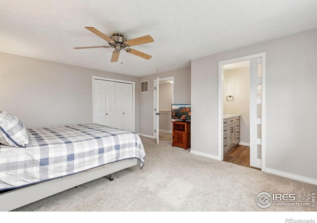 bedroom featuring light colored carpet, a closet, baseboards, ensuite bathroom, and ceiling fan