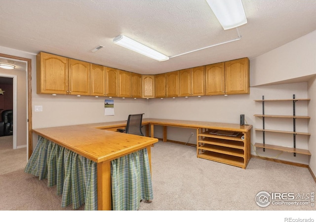 office area featuring light carpet, baseboards, and a textured ceiling