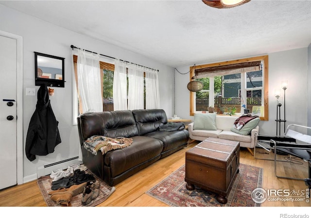 living room with baseboard heating, plenty of natural light, wood finished floors, and a textured ceiling