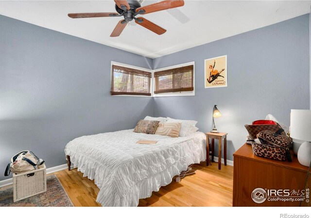 bedroom featuring baseboards, light wood finished floors, and a ceiling fan