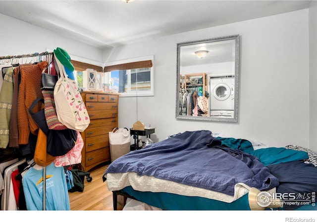 bedroom featuring wood finished floors and stacked washing machine and dryer