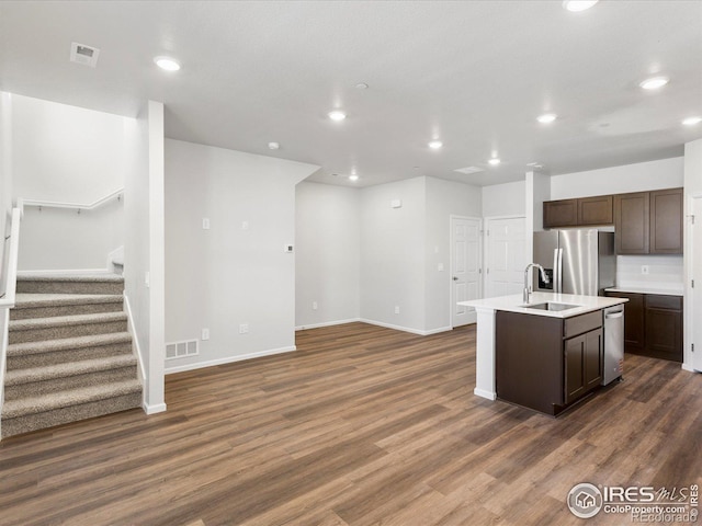 kitchen featuring appliances with stainless steel finishes, a sink, dark brown cabinets, recessed lighting, and baseboards