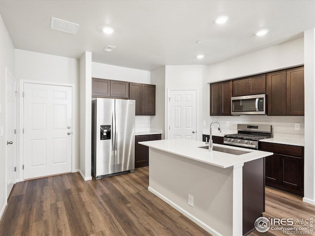 kitchen featuring appliances with stainless steel finishes, a sink, dark brown cabinets, dark wood-type flooring, and light countertops