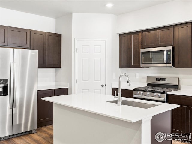 kitchen featuring stainless steel appliances, dark brown cabinets, a sink, light countertops, and dark wood finished floors