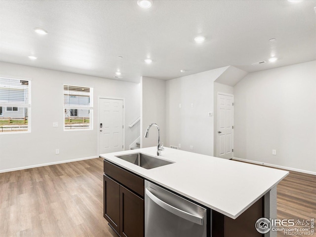 kitchen featuring stainless steel dishwasher, a sink, light countertops, light wood finished floors, and recessed lighting