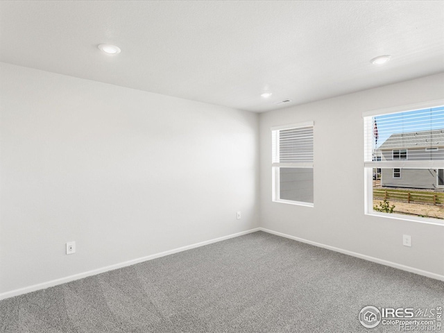 empty room with carpet flooring, baseboards, and recessed lighting