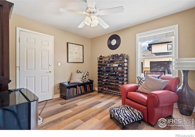 living area featuring light wood-style floors and a ceiling fan