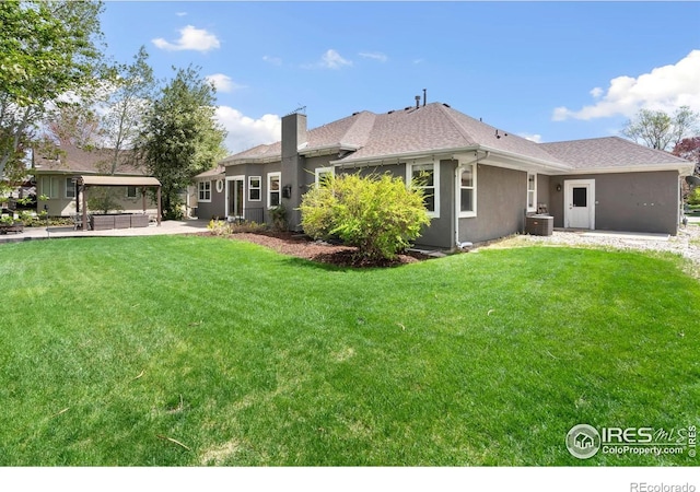 back of property with central AC unit, a yard, a gazebo, a chimney, and stucco siding