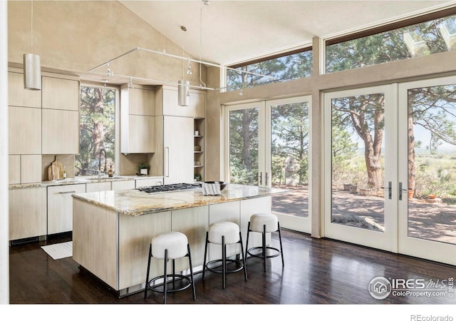 kitchen with a sink, modern cabinets, dark wood-style floors, a kitchen island, and high vaulted ceiling
