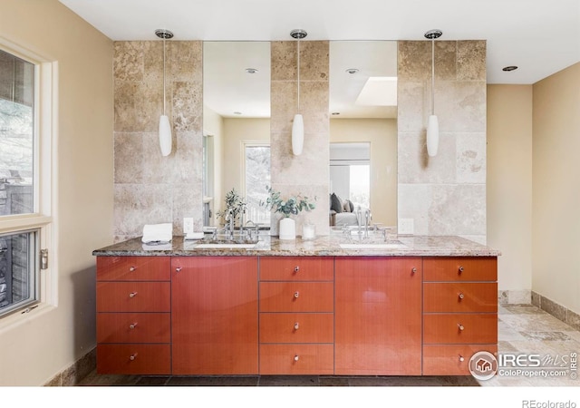 ensuite bathroom featuring double vanity and baseboards