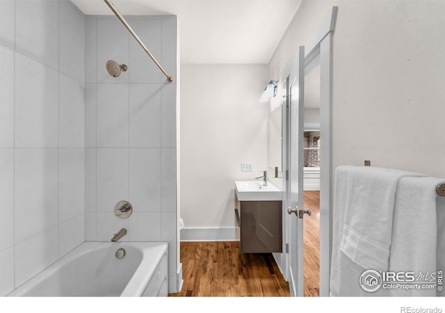 bathroom featuring wood finished floors, vanity, baseboards, and bathing tub / shower combination
