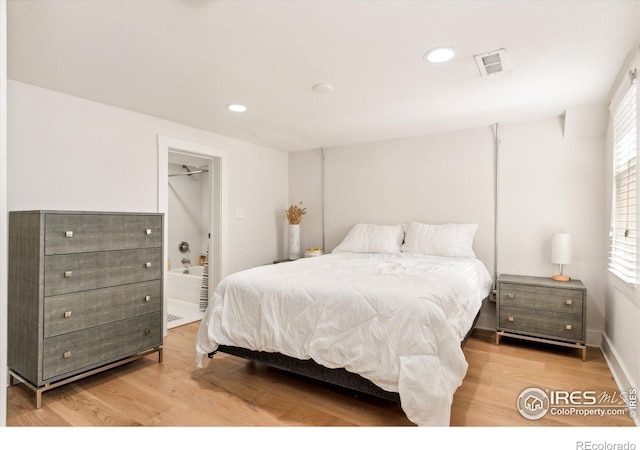 bedroom with light wood-style floors, recessed lighting, and ensuite bath