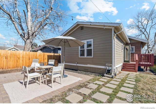 rear view of property featuring fence, a patio area, and a deck