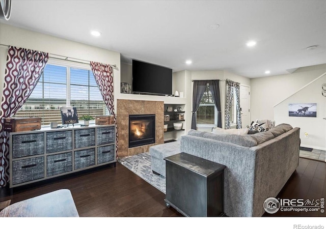 living area featuring dark wood-style floors, a tile fireplace, and recessed lighting