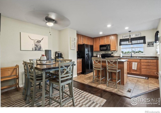 kitchen featuring black appliances, dark countertops, light wood finished floors, a kitchen island, and ceiling fan