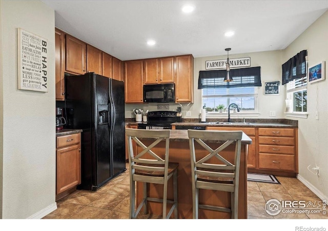 kitchen featuring black appliances, a sink, dark countertops, hanging light fixtures, and light tile patterned floors
