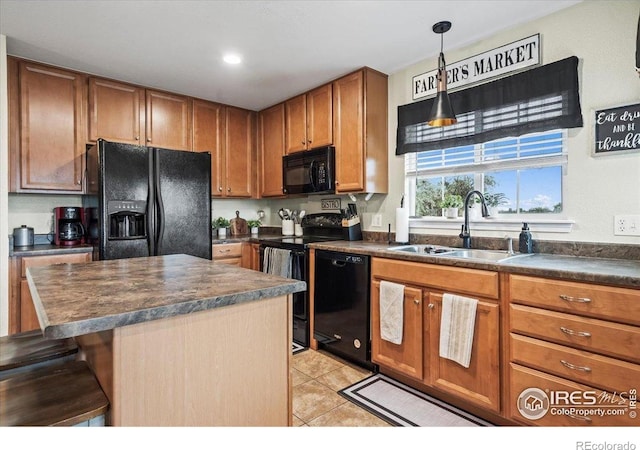 kitchen featuring black appliances, a sink, dark countertops, and brown cabinetry