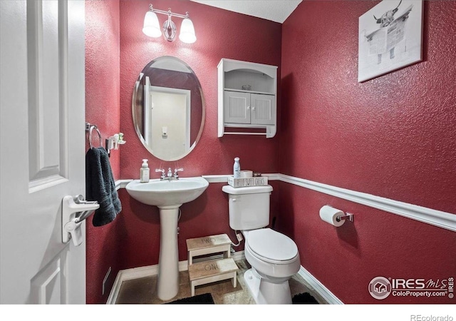 bathroom with toilet and a textured wall
