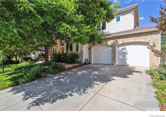 4059 Nevis St, Boulder, CO 80301 - view of property hidden behind natural elements with concrete driveway, a garage, and brick siding