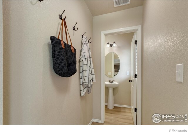 hall with wood finished floors, baseboards, and a sink