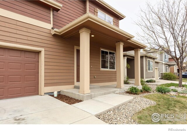 doorway to property with covered porch, driveway, and an attached garage