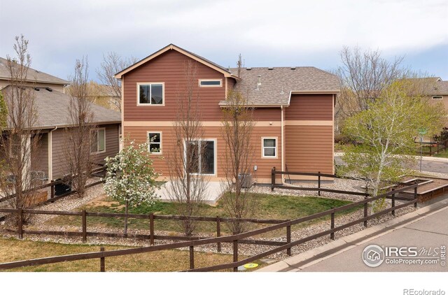 view of front of home featuring fence, a shingled roof, and cooling unit