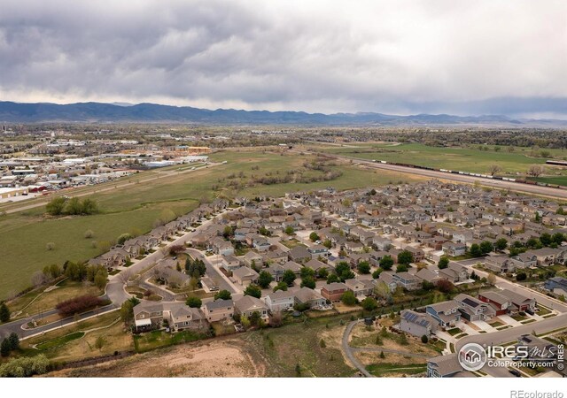 aerial view of property and surrounding area featuring nearby suburban area and a mountainous background