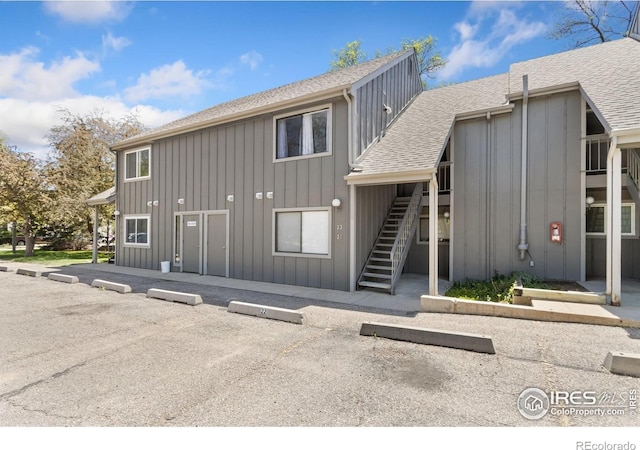 705 E Drake Rd Unit 22, Fort Collins, CO 80525 - back of property with roof with shingles, stairs, board and batten siding, and uncovered parking