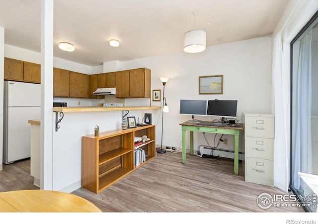 705 E Drake Rd Unit 22, Fort Collins, CO 80525 - kitchen featuring freestanding refrigerator, under cabinet range hood, brown cabinets, baseboard heating, and an office area