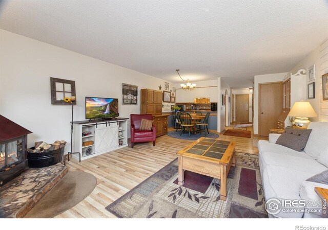 620 Macgregor Ave Unit 2, Estes Park, CO 80517 - living area with a chandelier, light wood finished floors, a wood stove, and a textured ceiling