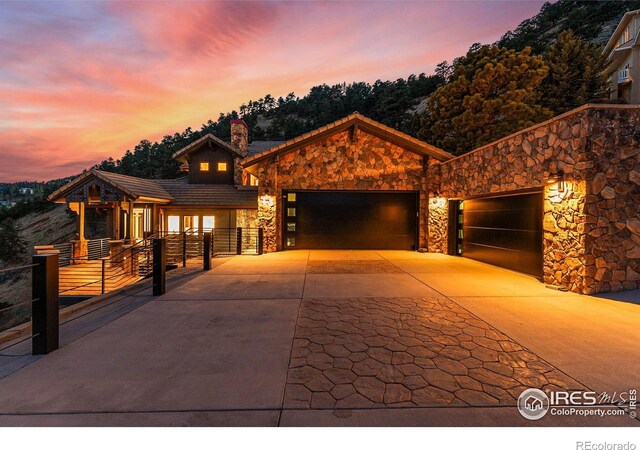 view of front facade with stone siding, concrete driveway, a garage, and fence