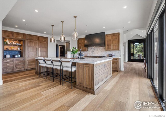 kitchen with custom exhaust hood, recessed lighting, light wood-style flooring, decorative backsplash, and open shelves