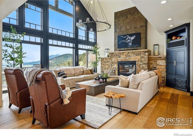 living area featuring wood finished floors, high vaulted ceiling, recessed lighting, a chandelier, and a fireplace