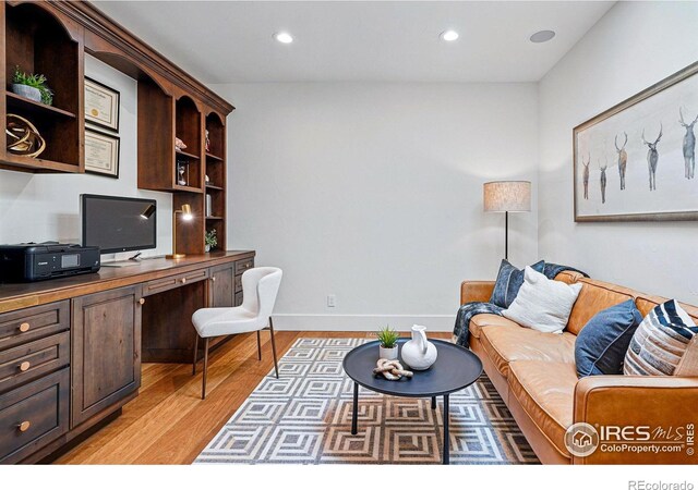 office space featuring light wood-type flooring, built in desk, recessed lighting, and baseboards
