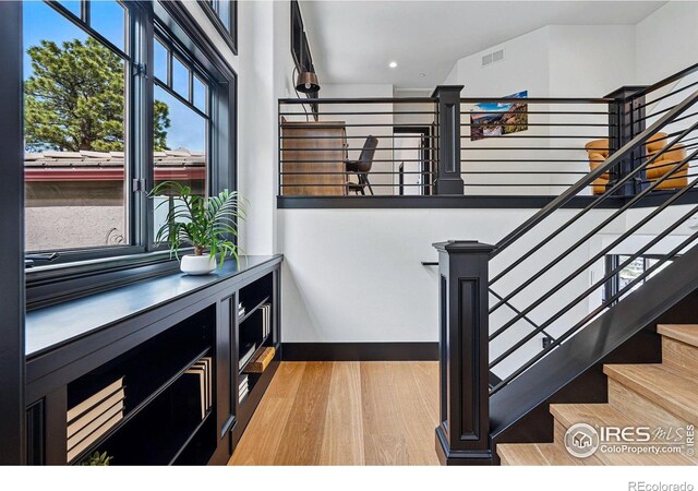 stairs with wood finished floors, baseboards, and recessed lighting