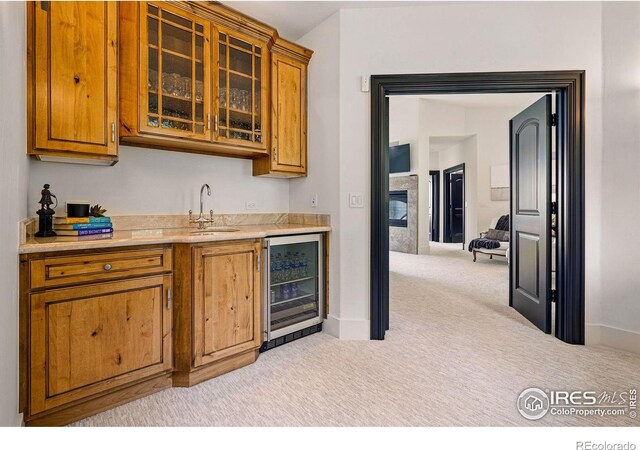 indoor wet bar with wine cooler, light colored carpet, a fireplace, and baseboards