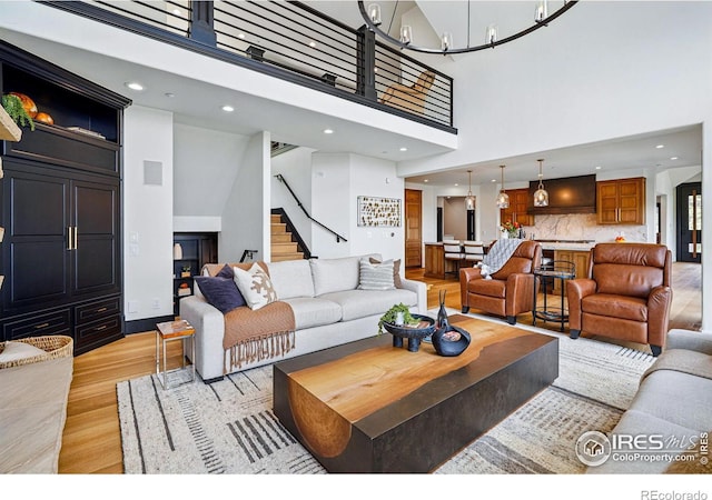 living room featuring light wood-style flooring, stairway, a towering ceiling, and recessed lighting