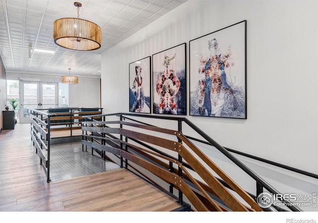 staircase with wood finished floors, french doors, and a chandelier